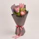 Elegant bouquet of pink protea flowers wrapped in gray paper